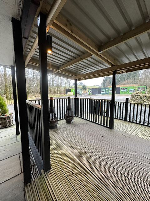 Covered deck with black painted posts and timber beam ceiling