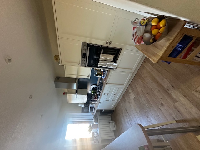 Modern kitchen installation with cream cabinetry and wood flooring