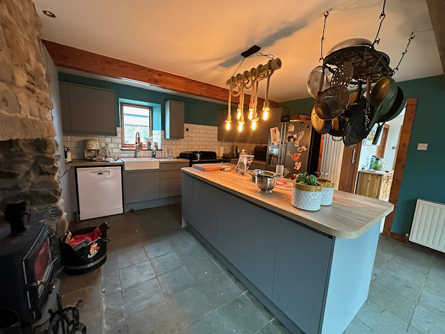 Rustic kitchen with blue cabinets, stone wall, and custom timber island