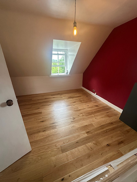 Oak flooring installation in loft room with feature wall